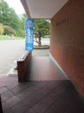 建物入口向って左側にスロープがあります。車いすの方はこちらのスロープを使ってください。スロープの奥が身障者駐車場です。